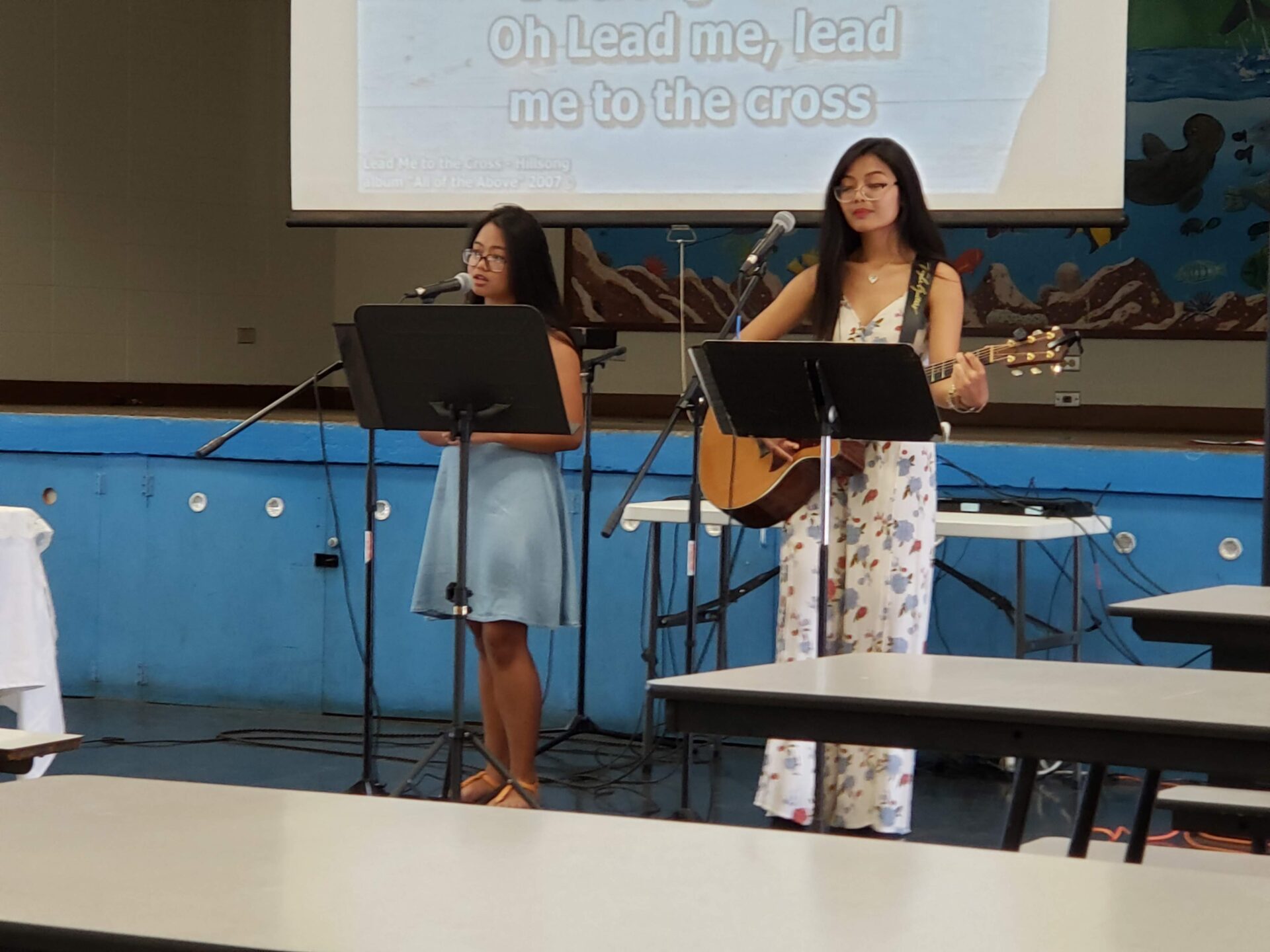 Two girls sing a song at an event.